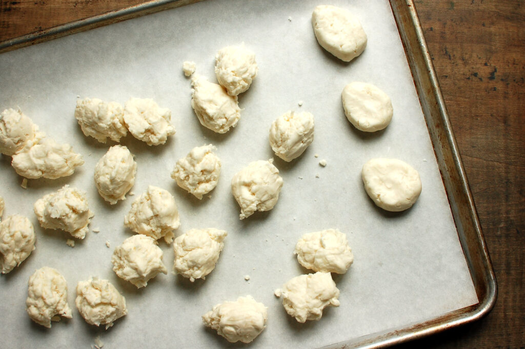 Scooping and shaping coconut cream Easter eggs by hand into rounds, then shaping into eggs before chilling on a sheet pan