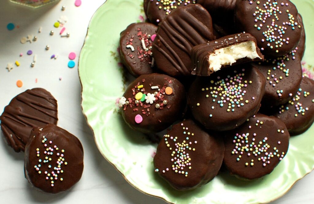 Homemade chocolate-covered coconut cream eggs with a bite taken out, showing the moist coconut cream Easter egg center and dark chocolate coating.