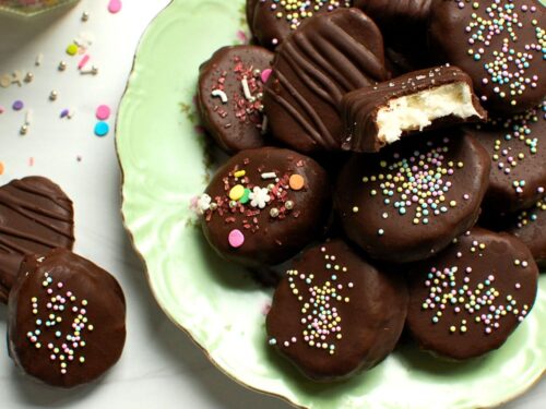 Homemade chocolate-covered coconut cream eggs with a bite taken out, showing the moist coconut cream Easter egg center and dark chocolate coating.