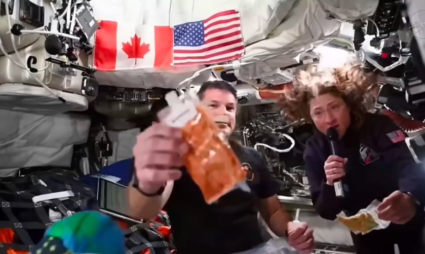 NASA Artemis II astronauts holding up a packet of shrimp cocktail space food