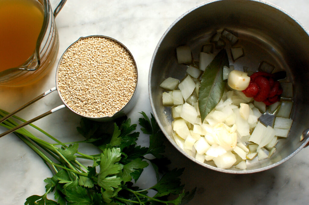 onion, garlic, bay leaf, and tomato paste in pot cooking before adding quinoa.